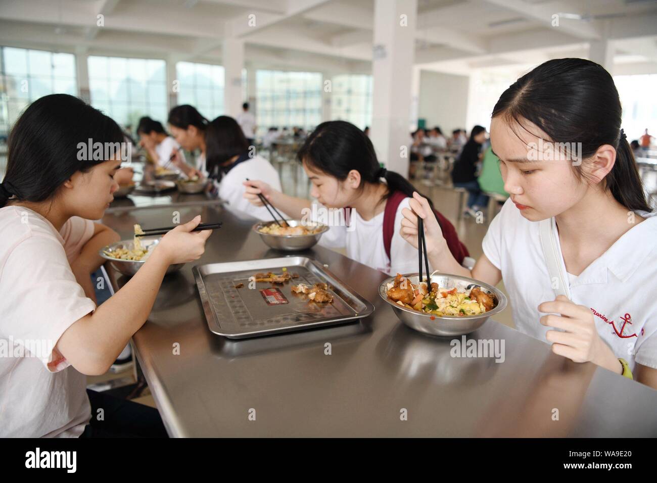 Studenti Cinesi mangiare il pranzo in mensa a un senior high school a Luocheng Mulam contea autonoma, a sud della Cina di Guangxi Zhuang Regione autonoma, Foto Stock