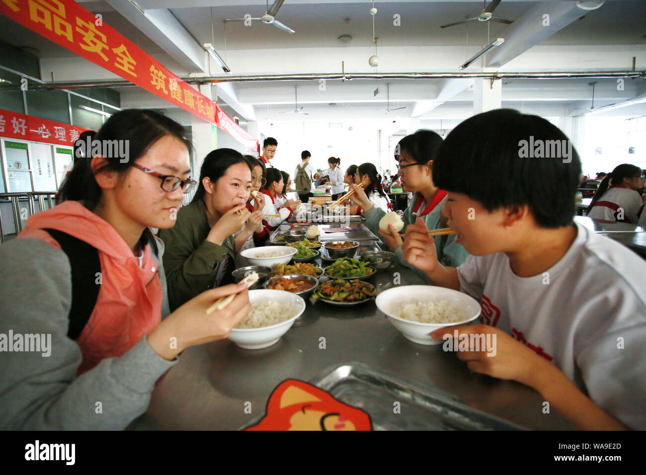 Studenti Cinesi che si siedono la fiera annua nazionale del collegio ingresso esame, meglio noto come gaokao, mangiare il pranzo in mensa presso una scuola superiore nel conteggio Zouping Foto Stock