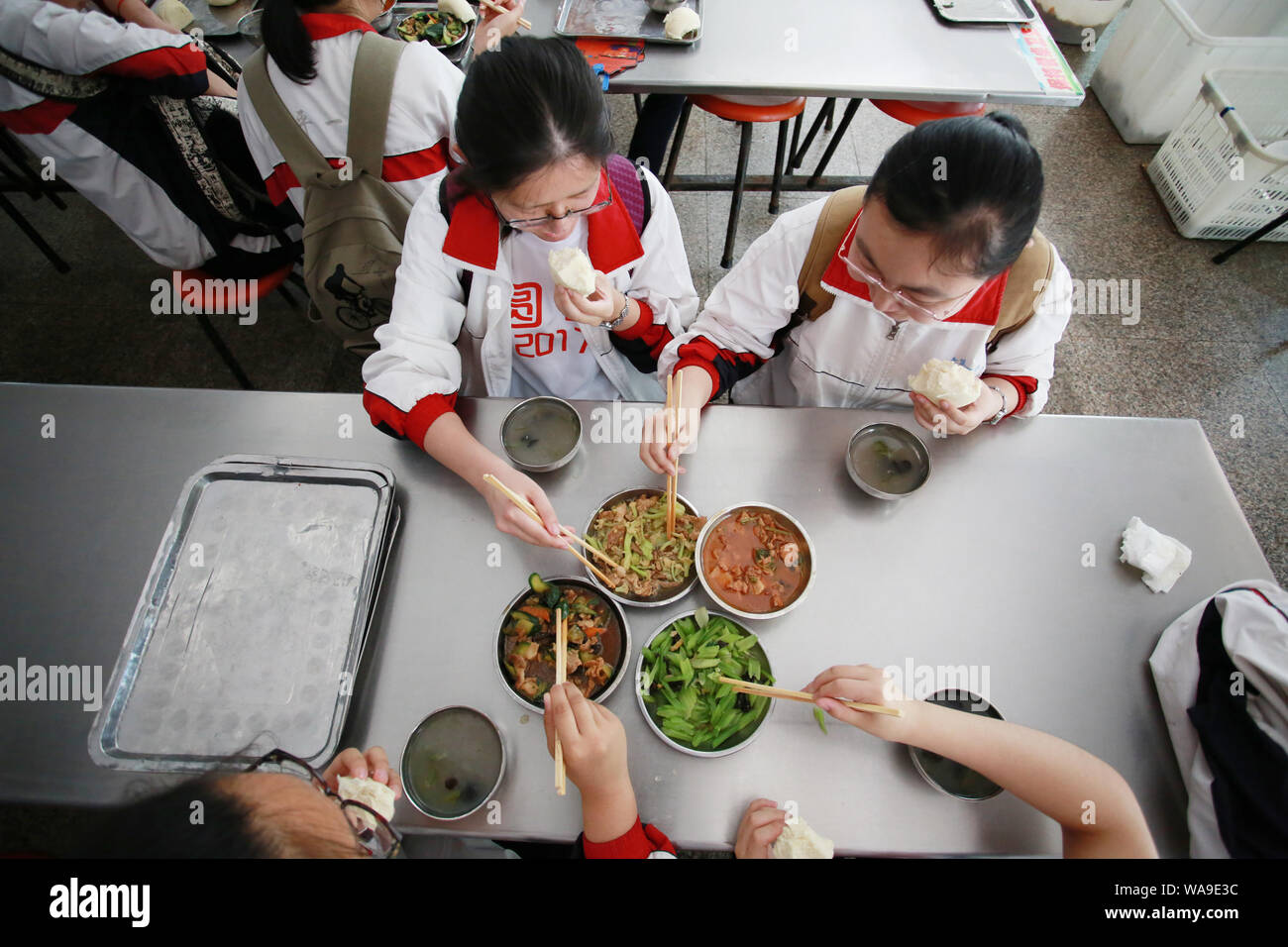 Studenti Cinesi che si siedono la fiera annua nazionale del collegio ingresso esame, meglio noto come gaokao, mangiare il pranzo in mensa presso una scuola superiore nel conteggio Zouping Foto Stock