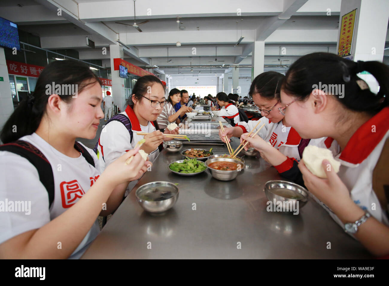 Studenti Cinesi che si siedono la fiera annua nazionale del collegio ingresso esame, meglio noto come gaokao, mangiare il pranzo in mensa presso una scuola superiore nel conteggio Zouping Foto Stock