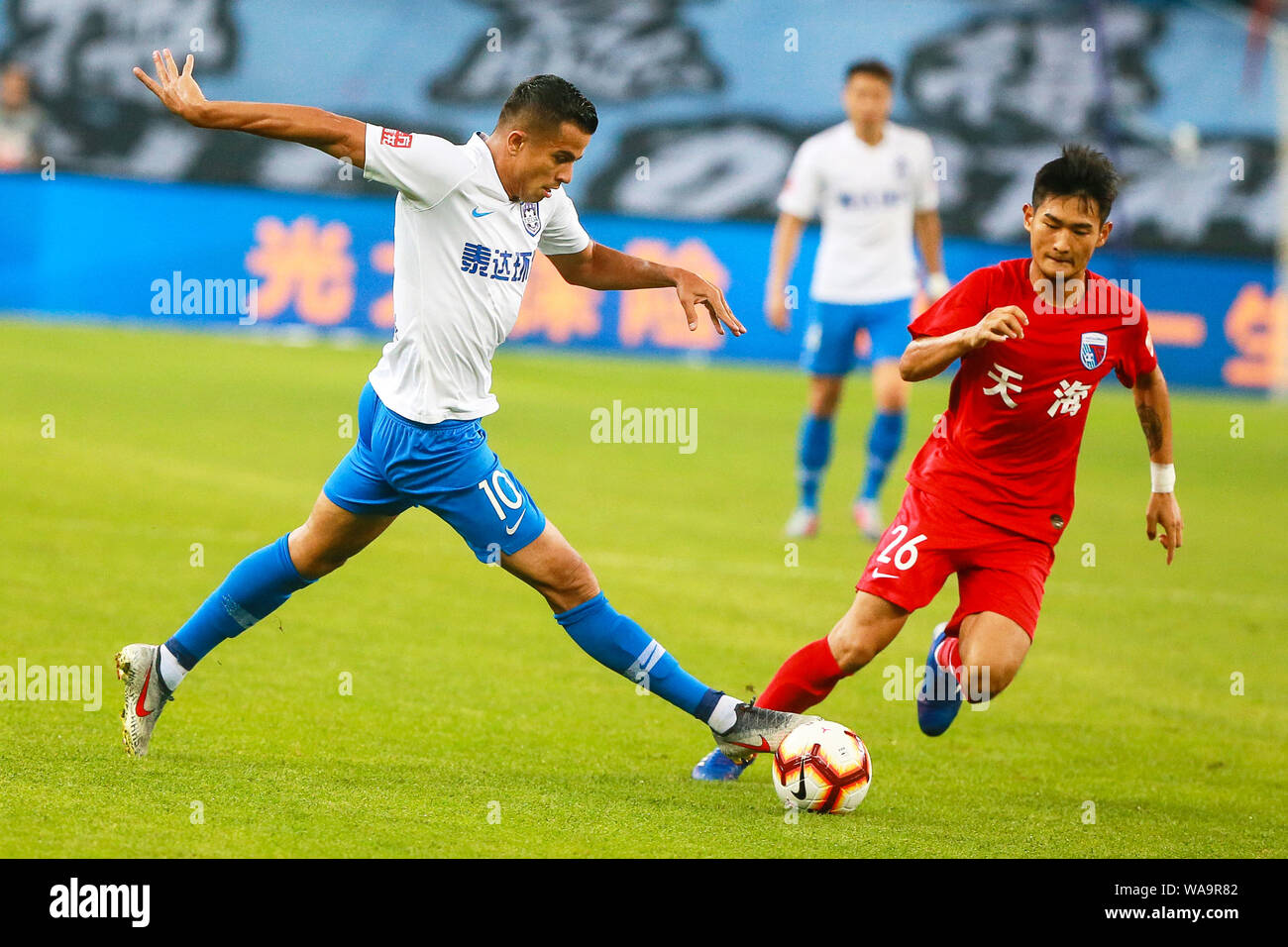 Il calcio brasiliano player Johnathan Aparecido da Silva, comunemente noto come Johnathan, sinistra, di Tianjin TEDA passa la palla contro un giocatore di Tianjin Foto Stock