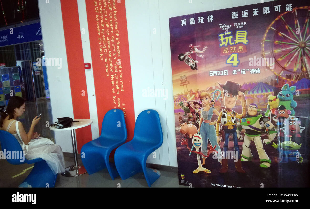 --FILE--un filmgoer attende accanto a un poster di American animated commedia film "Toy Story 4' in un cinema della città Yichang, centrale cinese della provincia di Hubei, 2 Foto Stock