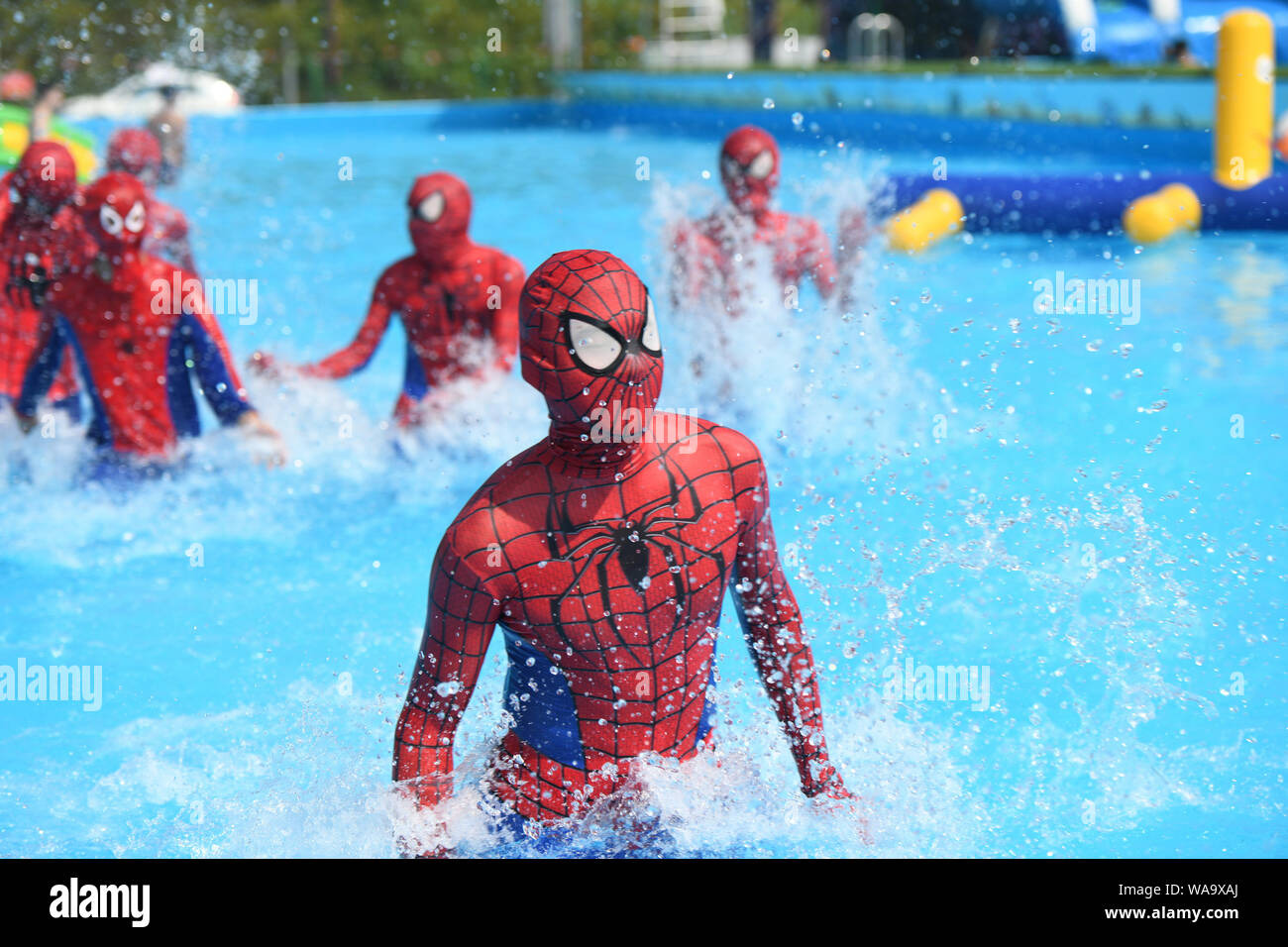 I membri del personale cinese vestiti come Spider-Man giocano in una piscina  durante un evento di mosche flash in un parco acquatico per sfuggire alle  onde di calore a Chongqing, Cina, 27