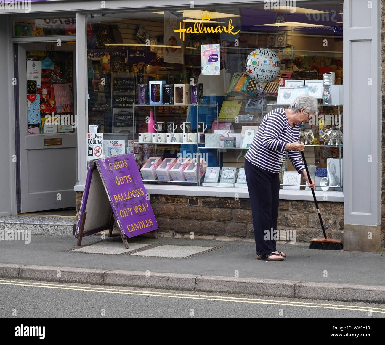 Una donna che spazia fino al di fuori di un negozio su Market Street, New Mills, Derbyshire Foto Stock