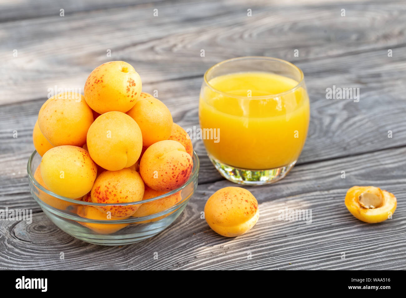 Albicocche giallo in recipiente di vetro e succo di frutta sul tavolo di legno Foto Stock