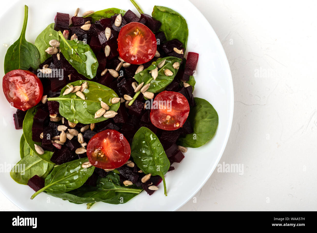 Una sana alimentazione vegetariana. Insalata con barbabietola, spinaci, pomodorini e semi. Foto Stock