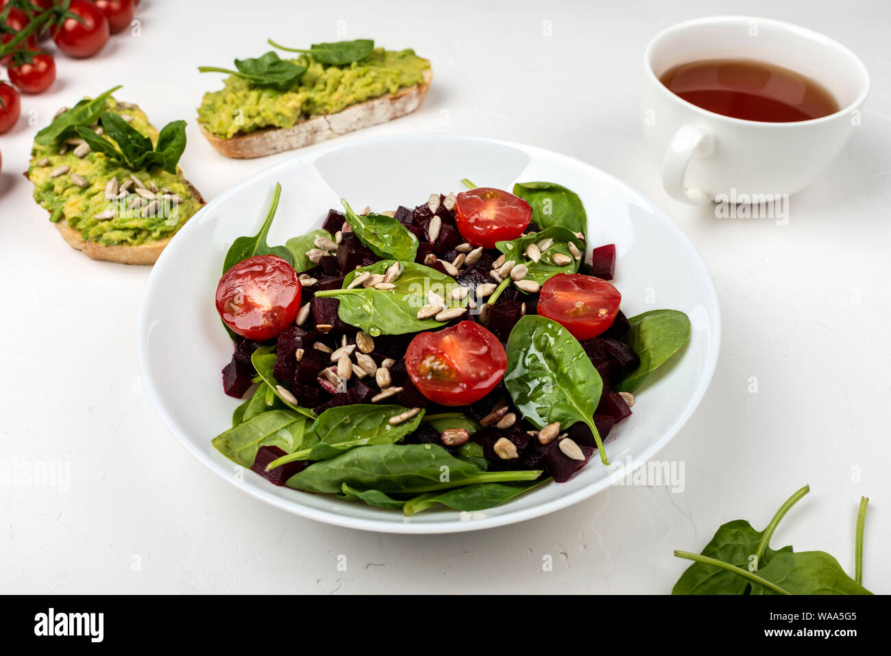Una sana alimentazione vegetariana. Insalata con barbabietola, spinaci, pomodorini e semi. Foto Stock