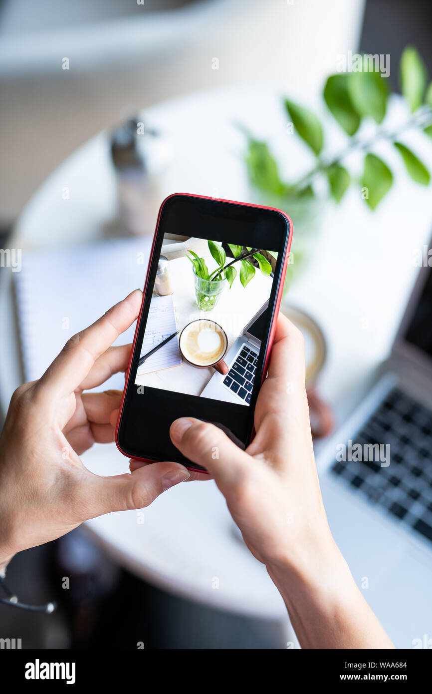 Le mani del giovane femmina smartphone tenuta sopra il tavolo mentre si fotografa Foto Stock