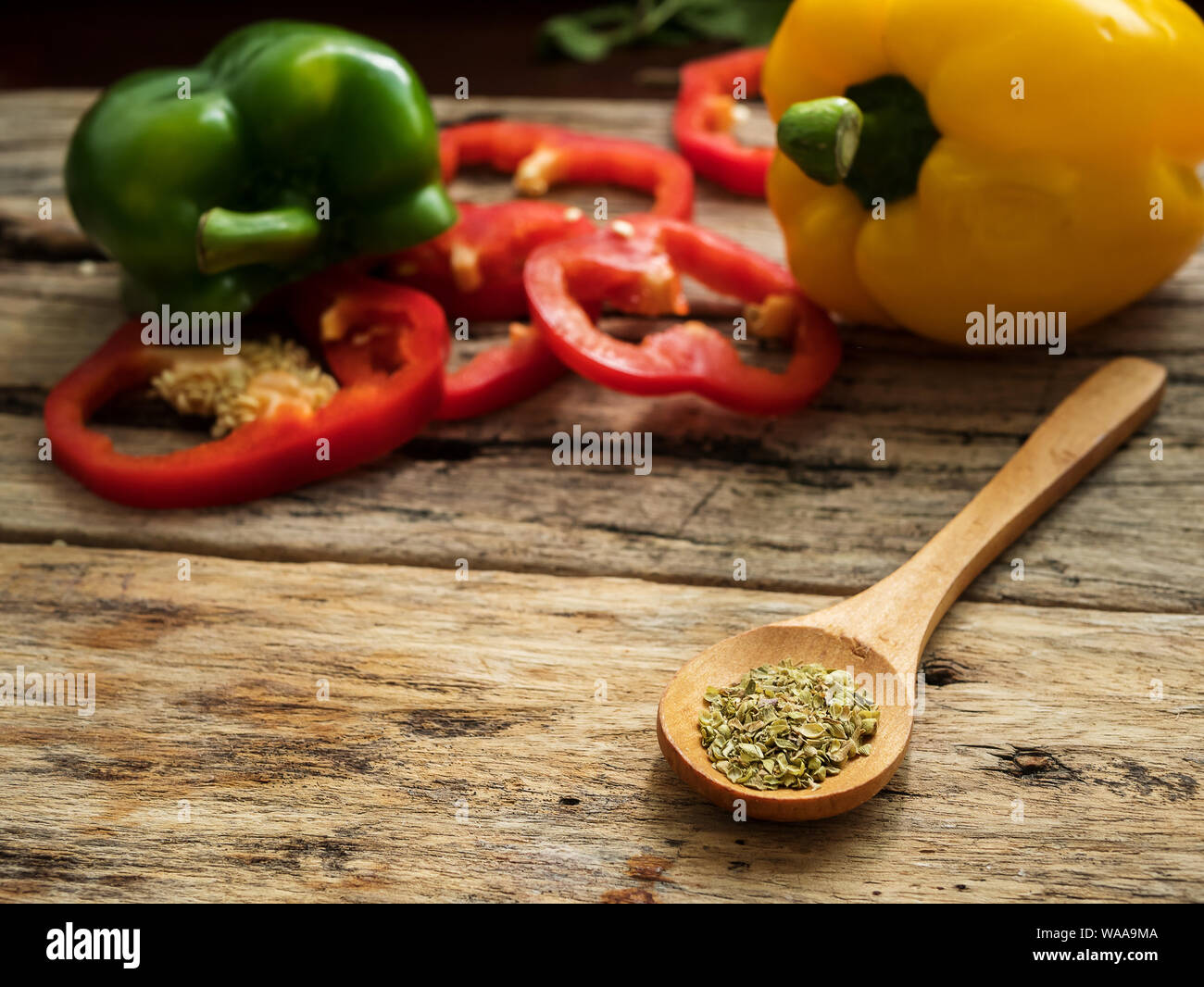 Chiudere il cucchiaio di legno con utensili erbe , colorato il peperone in background. cibo sano menu e concetto di cucina a vista Foto Stock