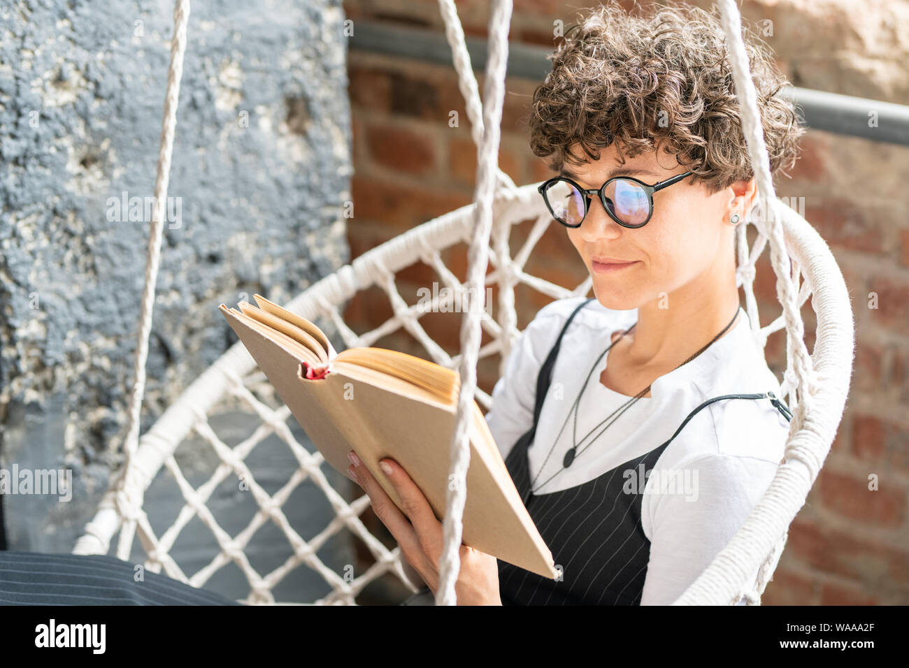 Piuttosto lo studente in occhiali lettura prenota at home Foto Stock