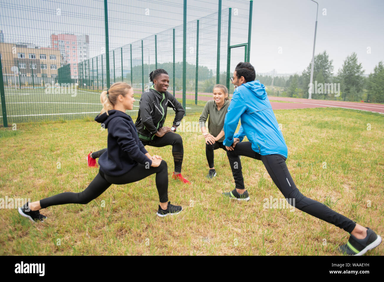 Gruppo di giovani multiculturale di gente amichevole facendo esercizio di stretching per le gambe Foto Stock