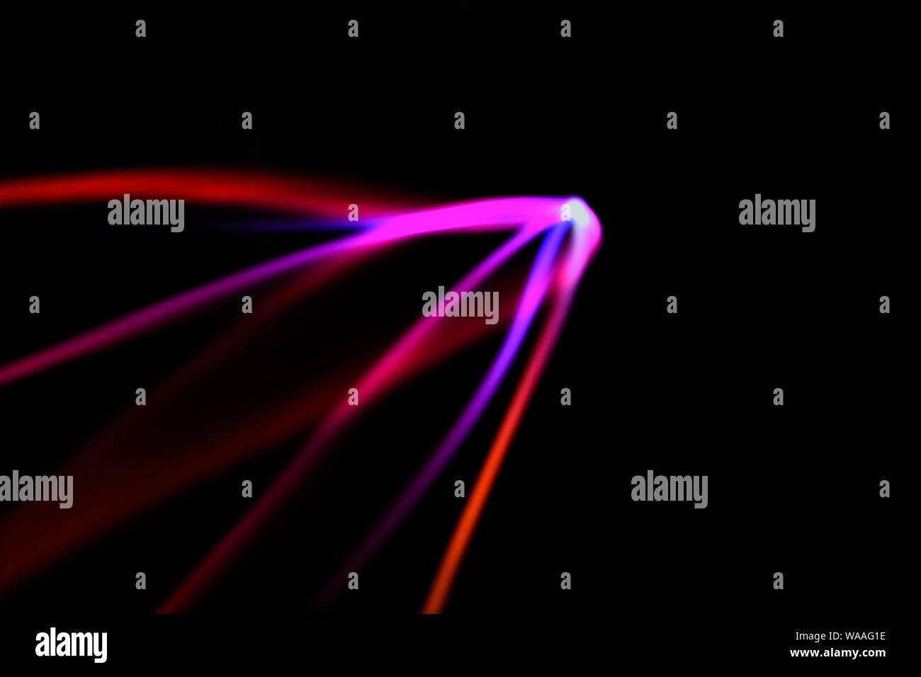 Incandescente neon linee su uno sfondo nero. Multicolor a forma di stella linee sfocati. Sfocato sfondo astratto. Foto Stock