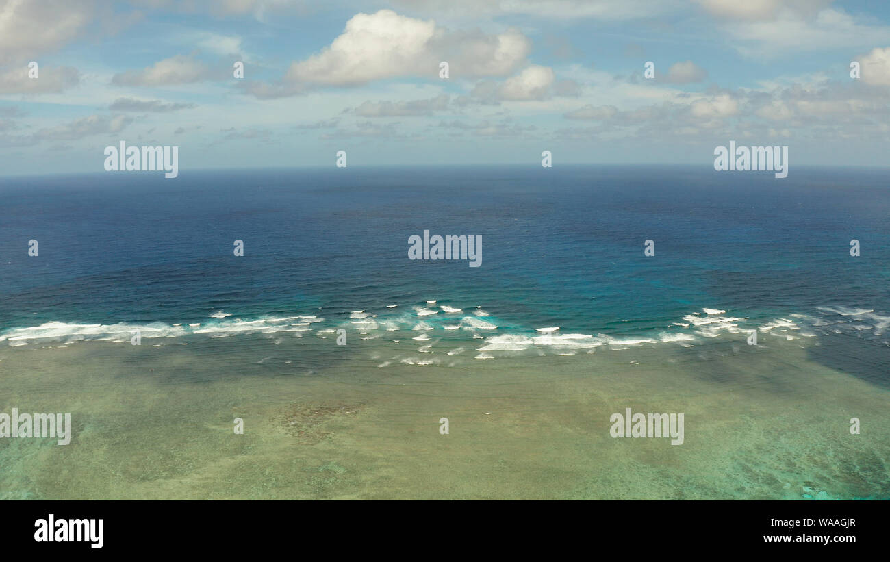 La superficie del mare con onde contro il cielo blu con nuvole, vista dall'alto. Blu acqua di mare con onde contro il cielo. Siargao, Filippine. Foto Stock