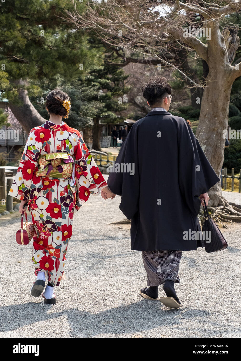 Una coppia Giapponese in kimonos cammina attraverso il Giardino Kenrokuen a Kanazawa, Giappone Foto Stock