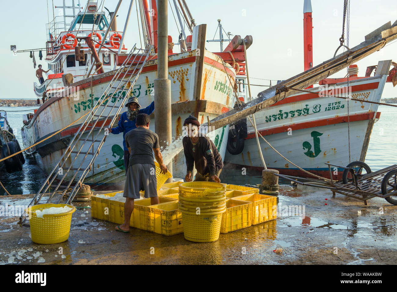 CHA AM, Tailandia - 10 dicembre 2018: mattina al porto. I marinai di un peschereccio carico di ghiaccio per congelare il pesce Foto Stock