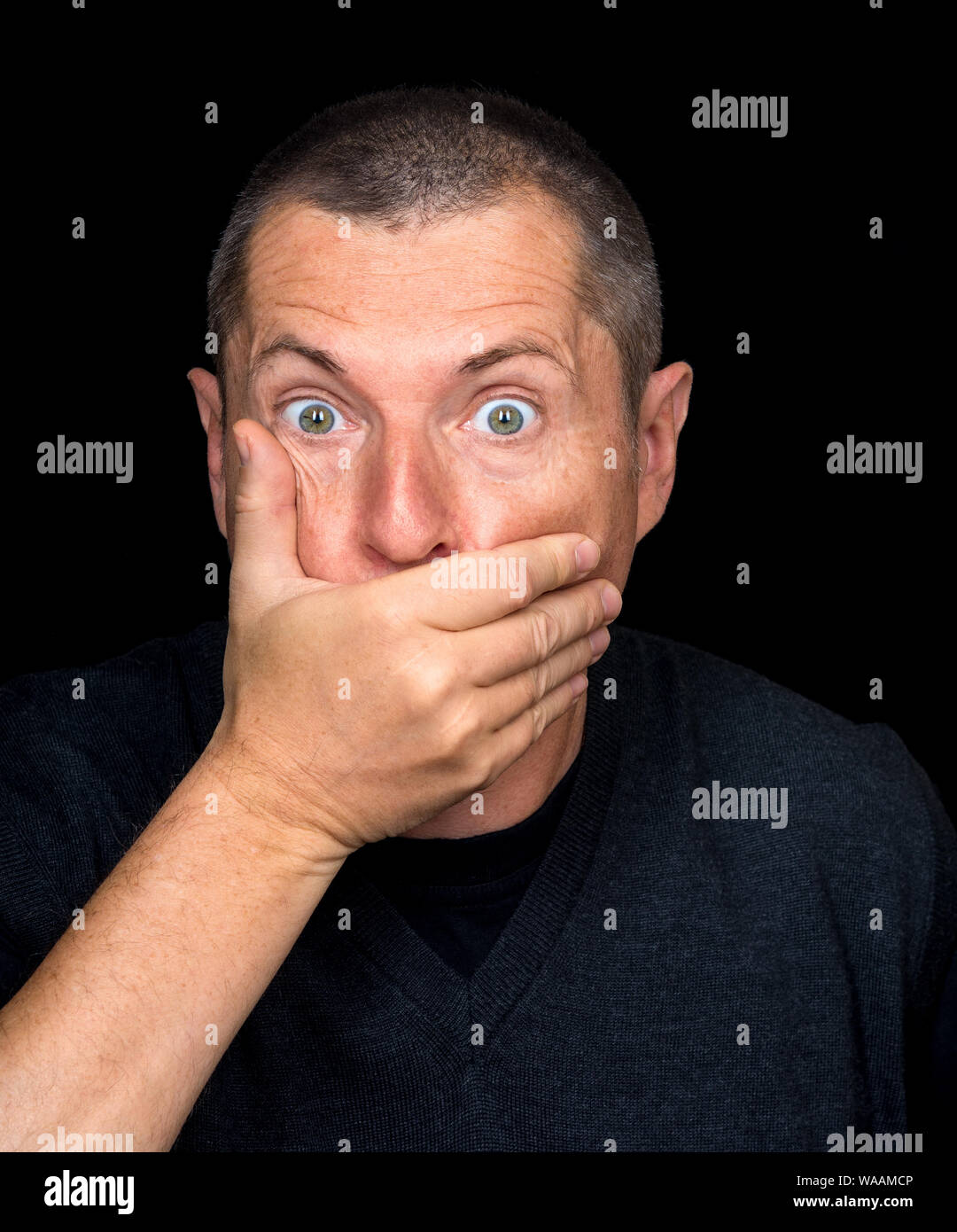 Ritratto di un uomo con emozioni grottesche su sfondo nero Foto Stock