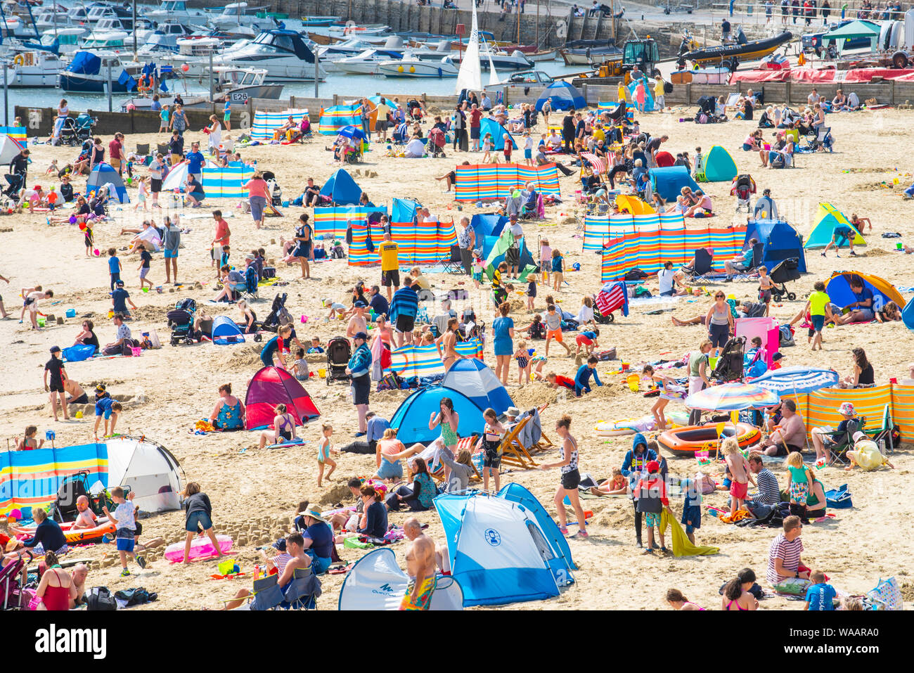 Lyme Regis, Dorset, Regno Unito. 19 agosto 2019. Regno Unito: Meteo Beachgoers e turisti affollano la spiaggia sabbiosa a pictureseque resort di Lyme Regis come un sole estivo torna dopo un fine settimana di pioggia e vento. Abbondanza di sole caldo e cielo blu sono previsioni meteo nella corsa fino a Ferragosto weekend. Credito: Celia McMahon/Alamy live news. Foto Stock