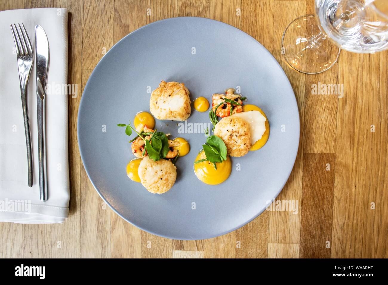 Colpo di pollo e gamberi con una verdura foglia su una piastra rotonda blu Foto Stock