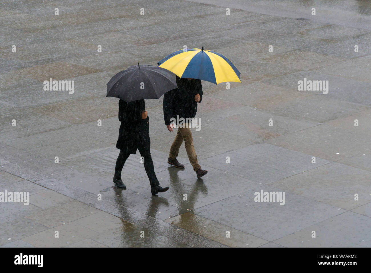 La gente camminare sotto la pioggia, Trafalgar Square, Londra, Gran Bretagna. Foto Stock