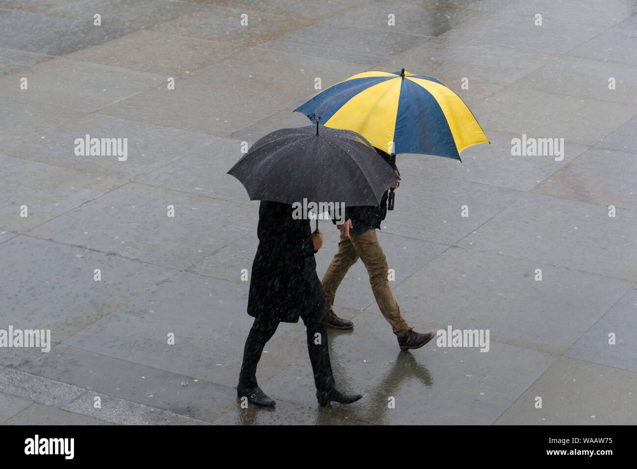 La gente camminare sotto la pioggia, Trafalgar Square, Londra, Gran Bretagna. Foto Stock