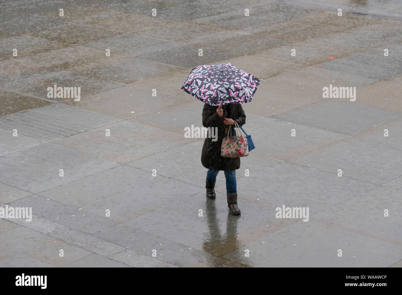 La gente camminare sotto la pioggia, Trafalgar Square, Londra, Gran Bretagna. Foto Stock