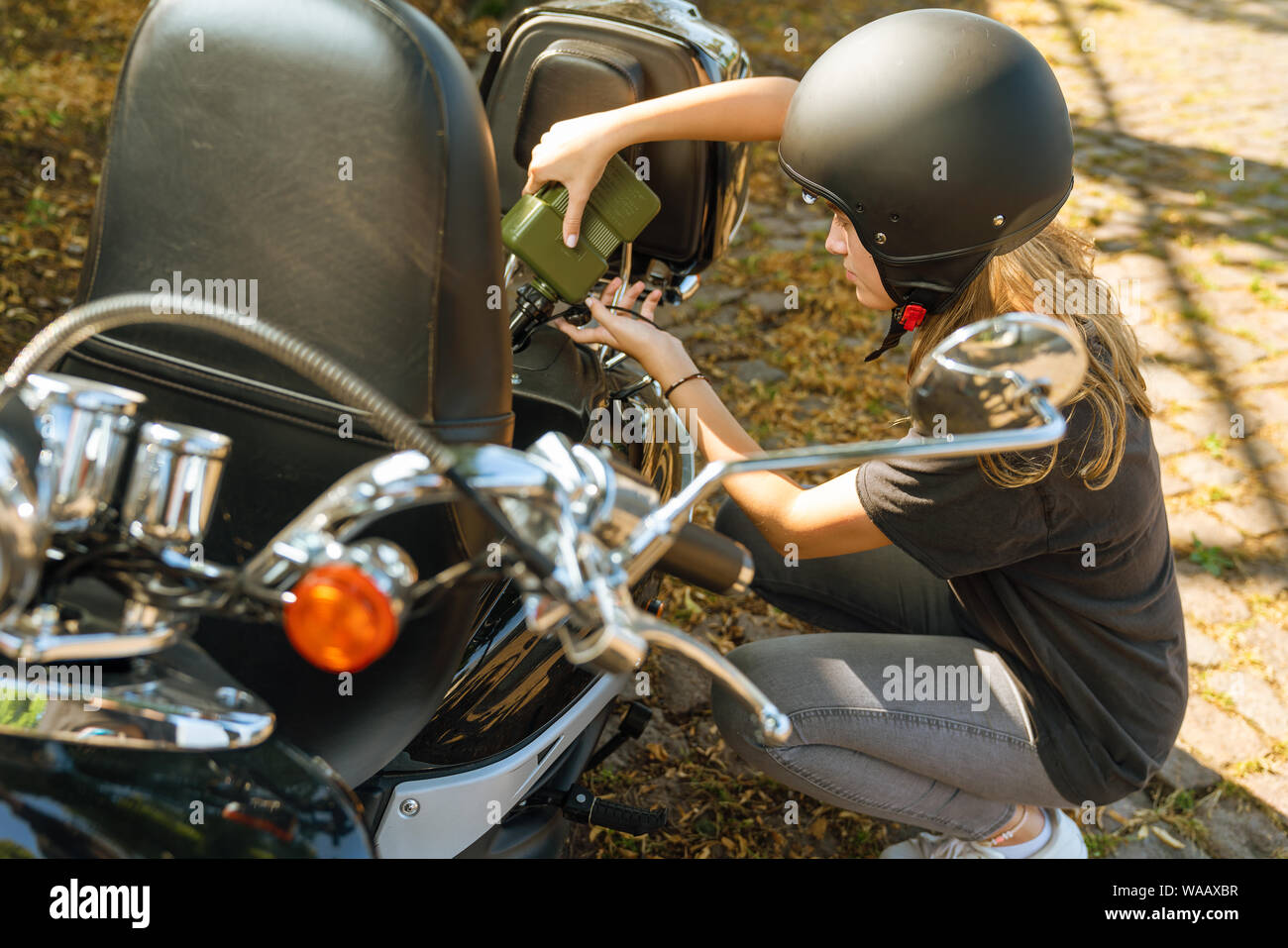 Giovane donna riempie il combustibile nel suo scooter a mano Foto Stock