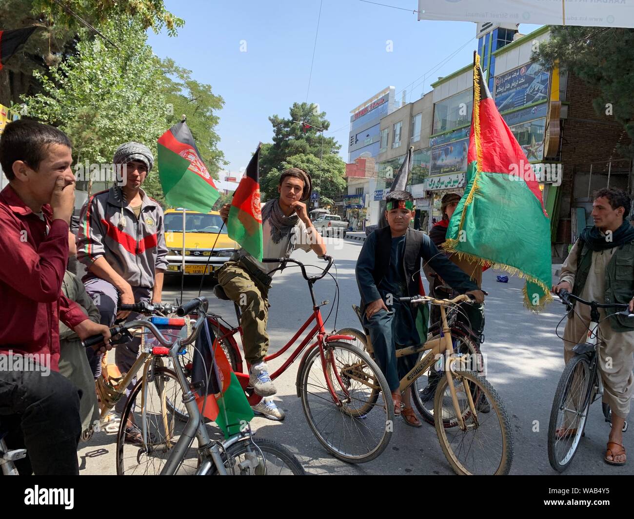 A Kabul, Afghanistan. 19 Ago, 2019. Ragazzi afghani cavalcare le loro biciclette decorate con la bandiera della nazione attraverso il centro della città per celebrare il paese del centesimo anniversario dell indipendenza dal British. Credito: Mohammad Jawad/dpa/Alamy Live News Foto Stock