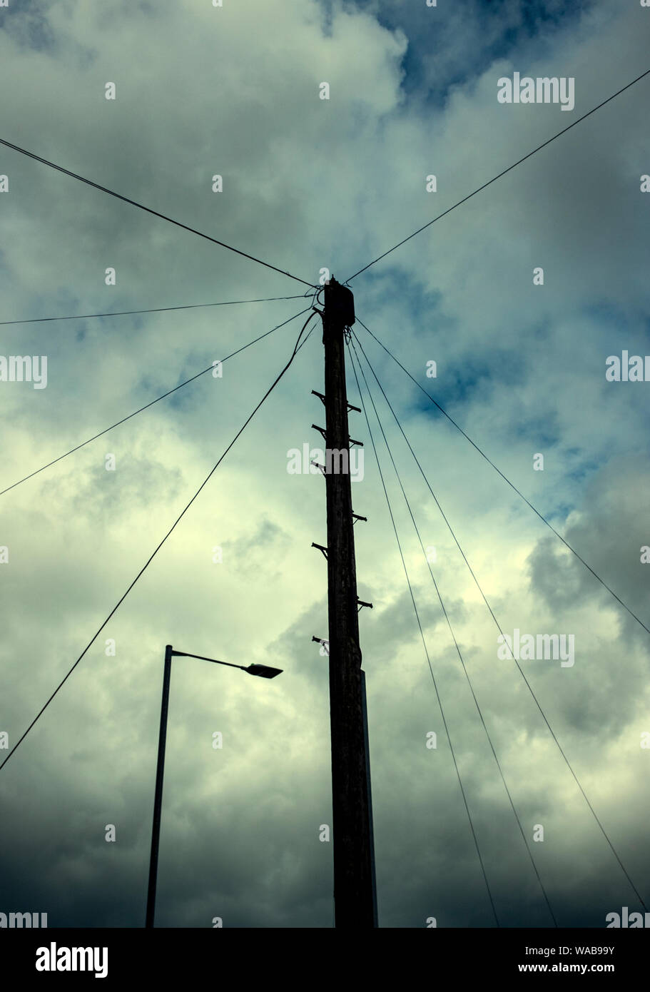 In legno palo del telegrafo con via la luce e il cielo nuvoloso REGNO UNITO Foto Stock