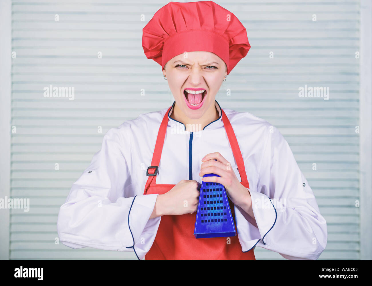 Cuocere nel ristorante, uniforme. ragazza nel grembiule e cappello. chef  professionale per la cottura in cucina. arrabbiato donna ama cucinare cibo  con grattugia. Utensili da cucina. La cucina gastronomica. Cucinare con  passione