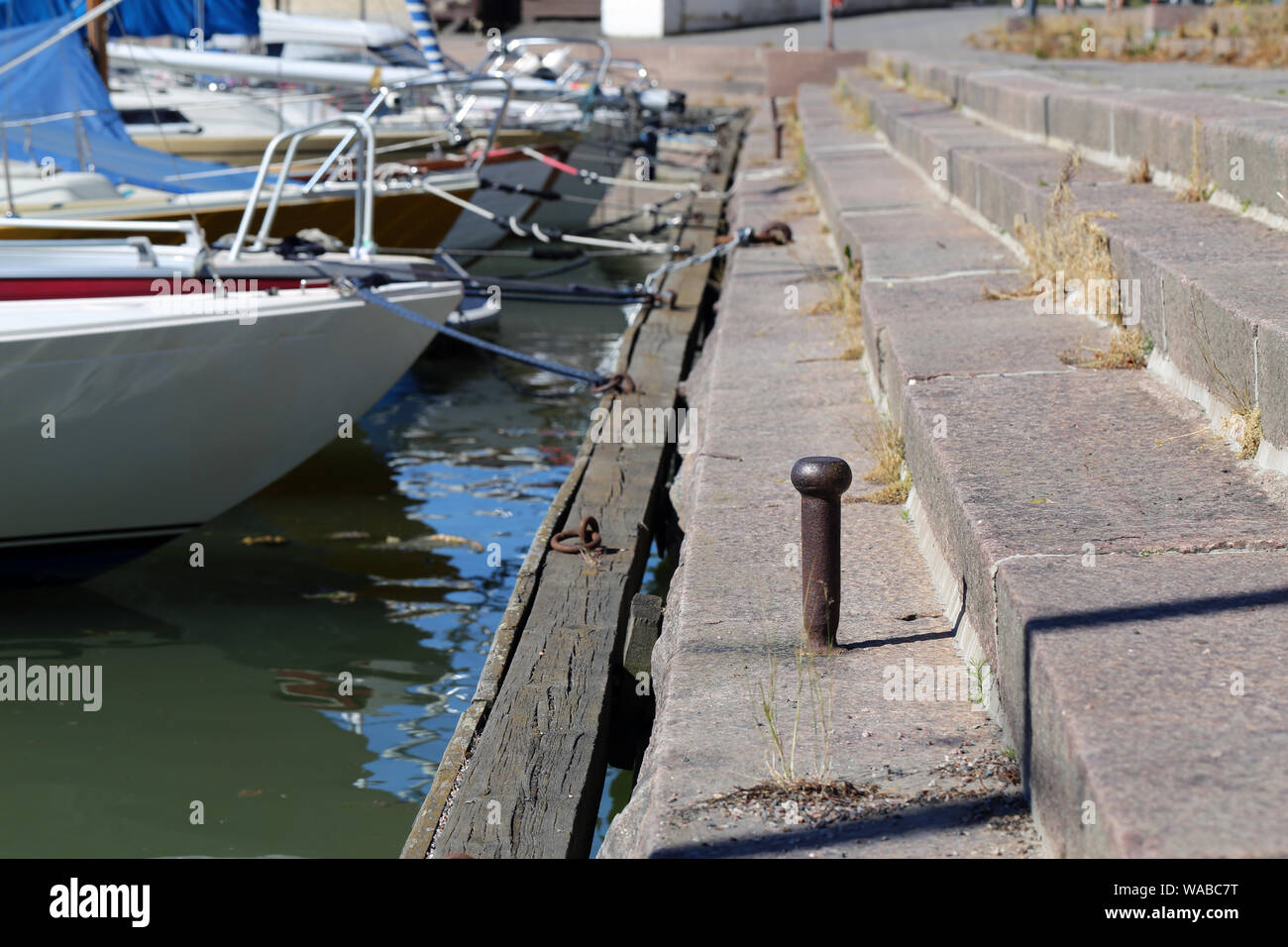 Un molo situato nella zona sud di Helsinki, Finlandia. Scale di pietra, acqua di mare e un sacco di diverse piccole imbarcazioni. In primo piano è possibile vedere il palo metallico. Foto Stock