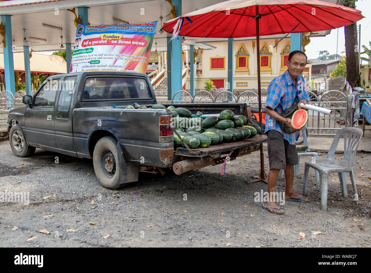 NAKHON NAYOK, Thailandia, Apr 03 2019, un'acqua-melone venditore mostra una fetta di acqua fresca melone. Un uomo vende angurie da un ritiro auto presso un mercato. Foto Stock