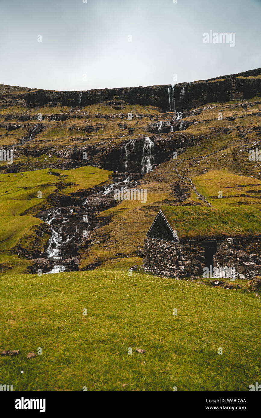 Vecchia casa nei pressi di una cascata in Saksun, Isole Faerøer Foto Stock