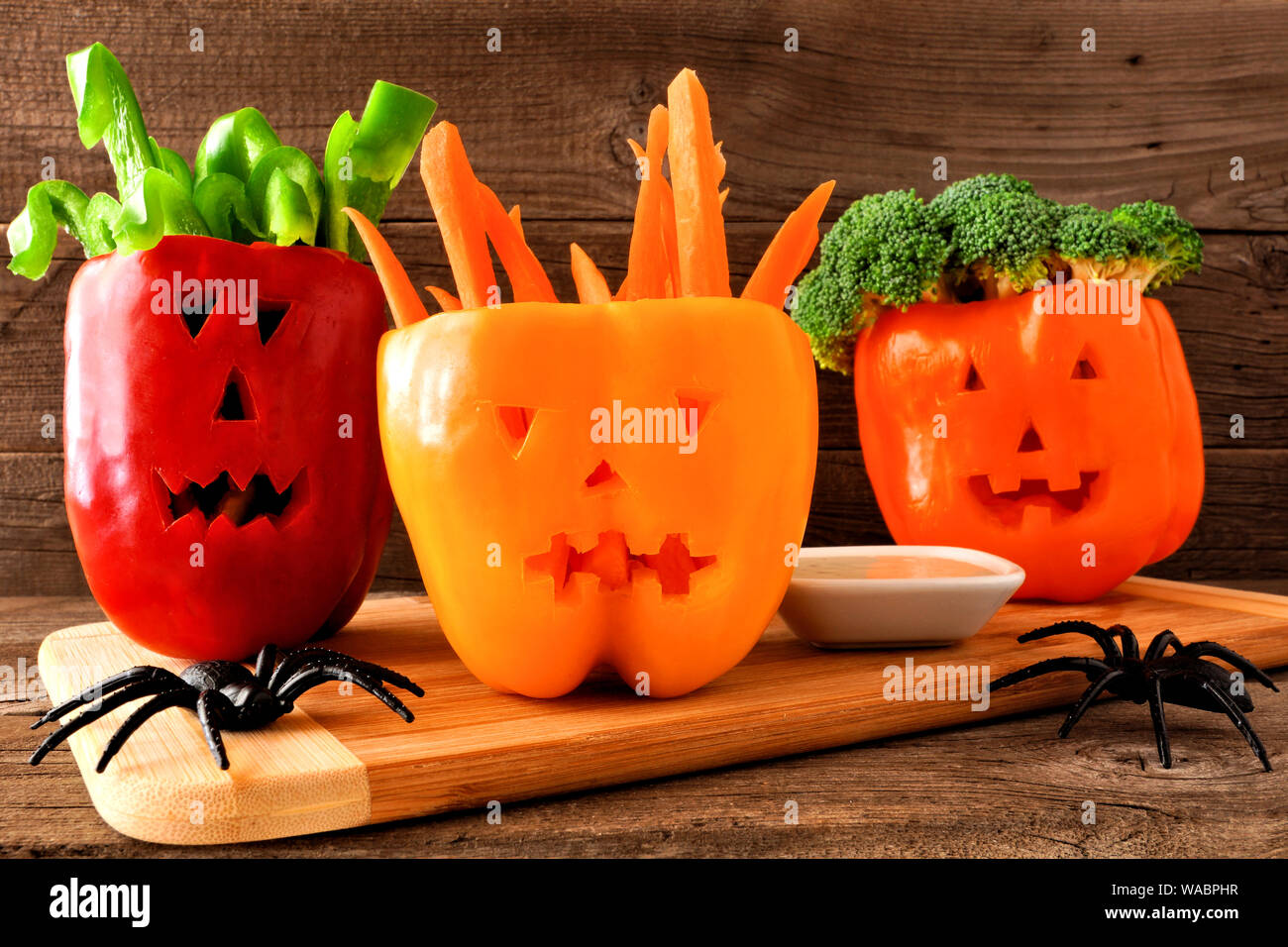 Halloween sano cibo. Verdure e immergere nel jack o Lantern i peperoni. Chiudere fino contro il legno rustico. Foto Stock