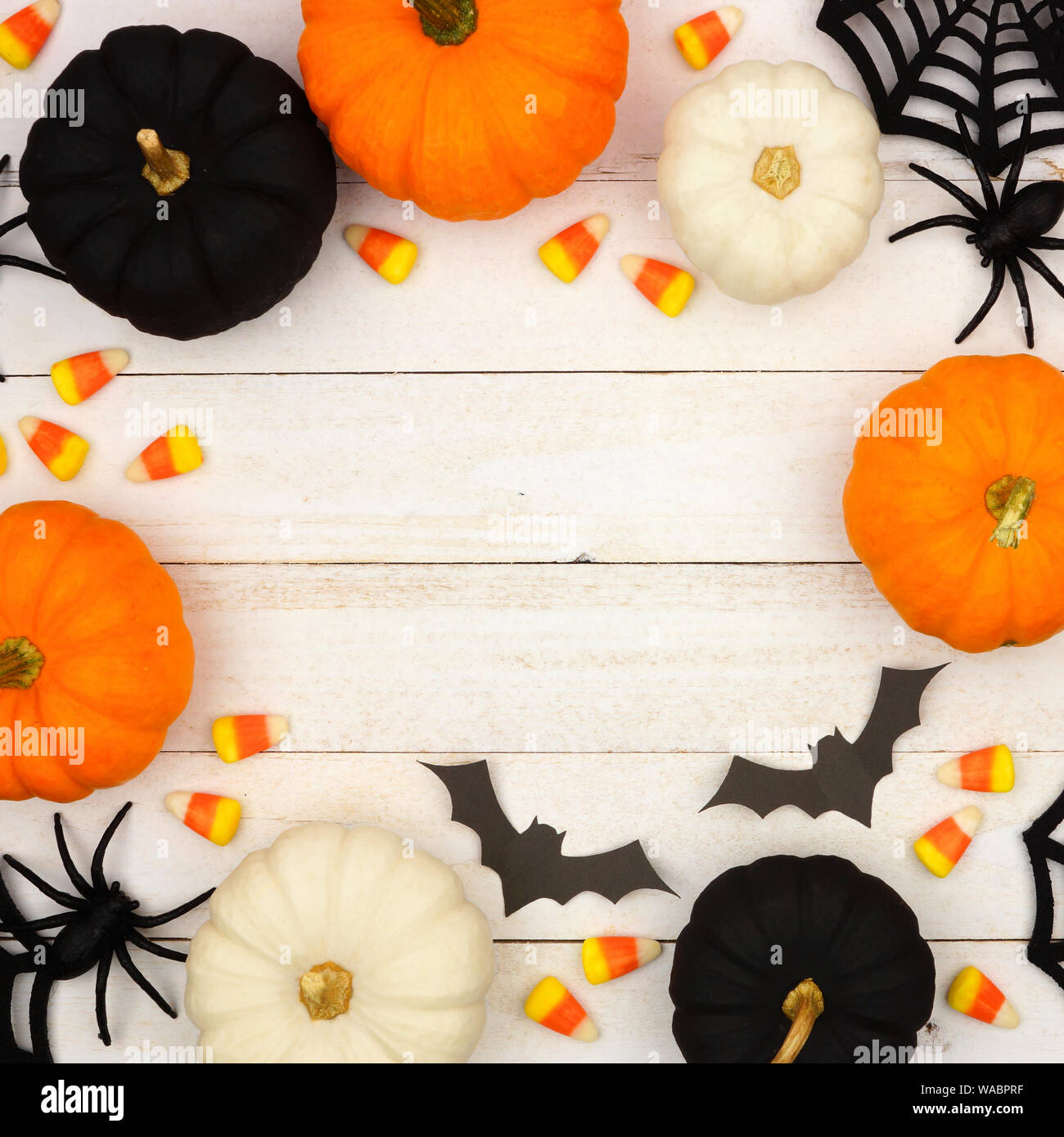 Halloween con telaio nero, arancione e un decor bianco e caramelle sopra un bianco sullo sfondo di legno. Vista da sopra con copia spazio. Foto Stock