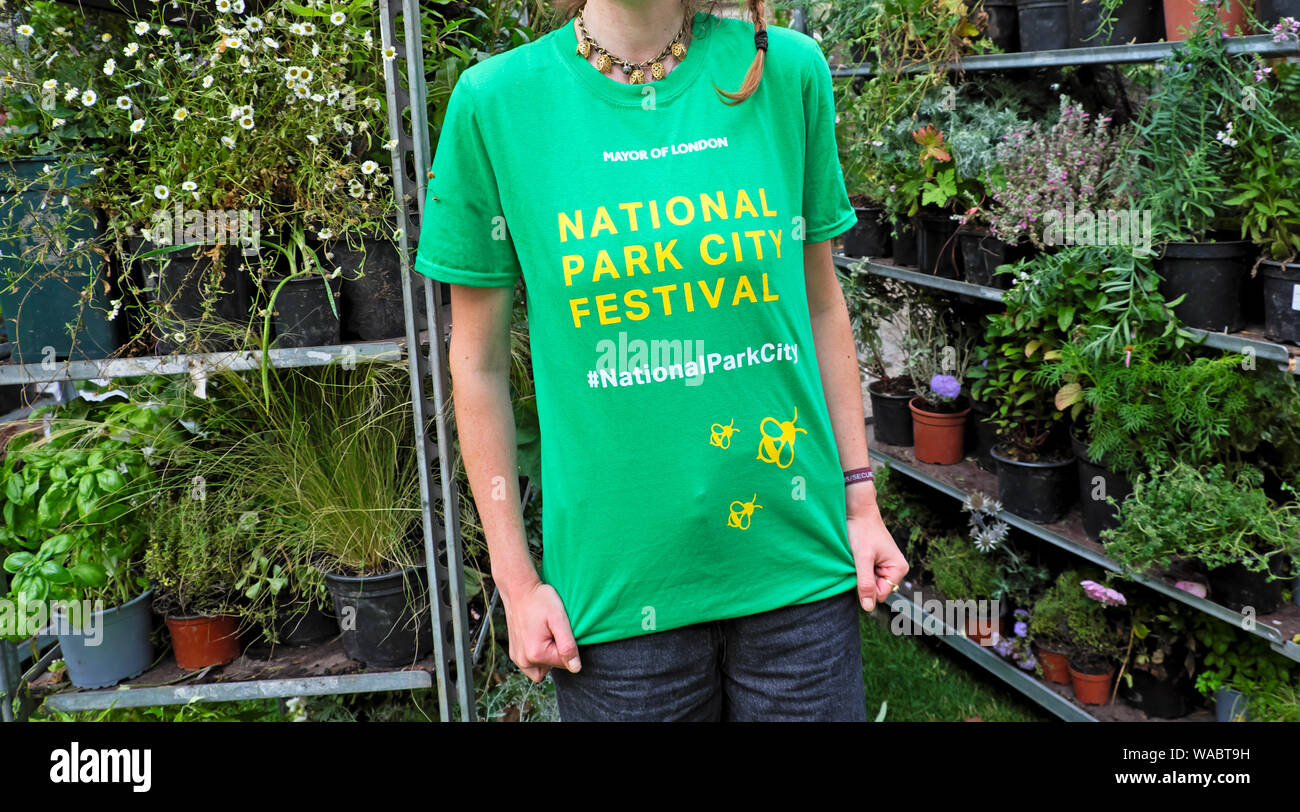 Giovane donna che indossa un verde parco nazionale Festa della città di t-shirt e piante sulle mensole nella città di Londra Inghilterra KATHY DEWITT Foto Stock