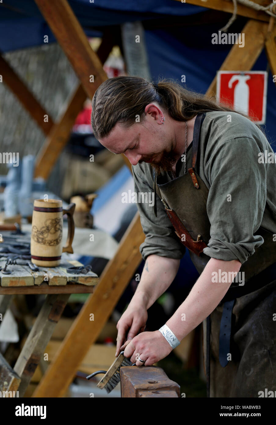 Hameenlinna Finlandia 08/17/2019 festa medievale con artigiano, cavalieri e animatori. Un fabbro spazzolando il suo lavoro Foto Stock