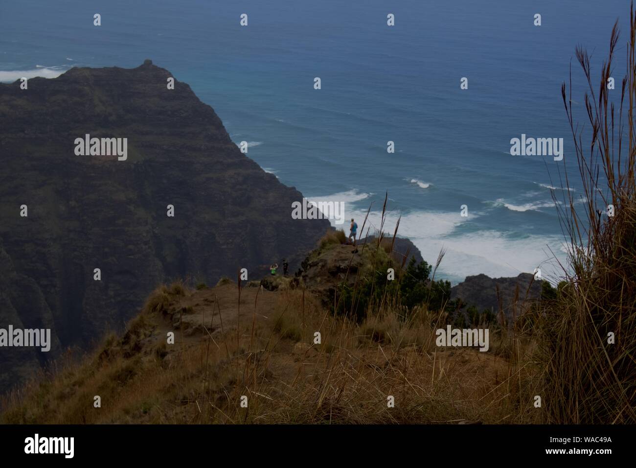 Guy si appoggia al di sotto di Kauai mountain top con l'oceano dietro di lui Foto Stock