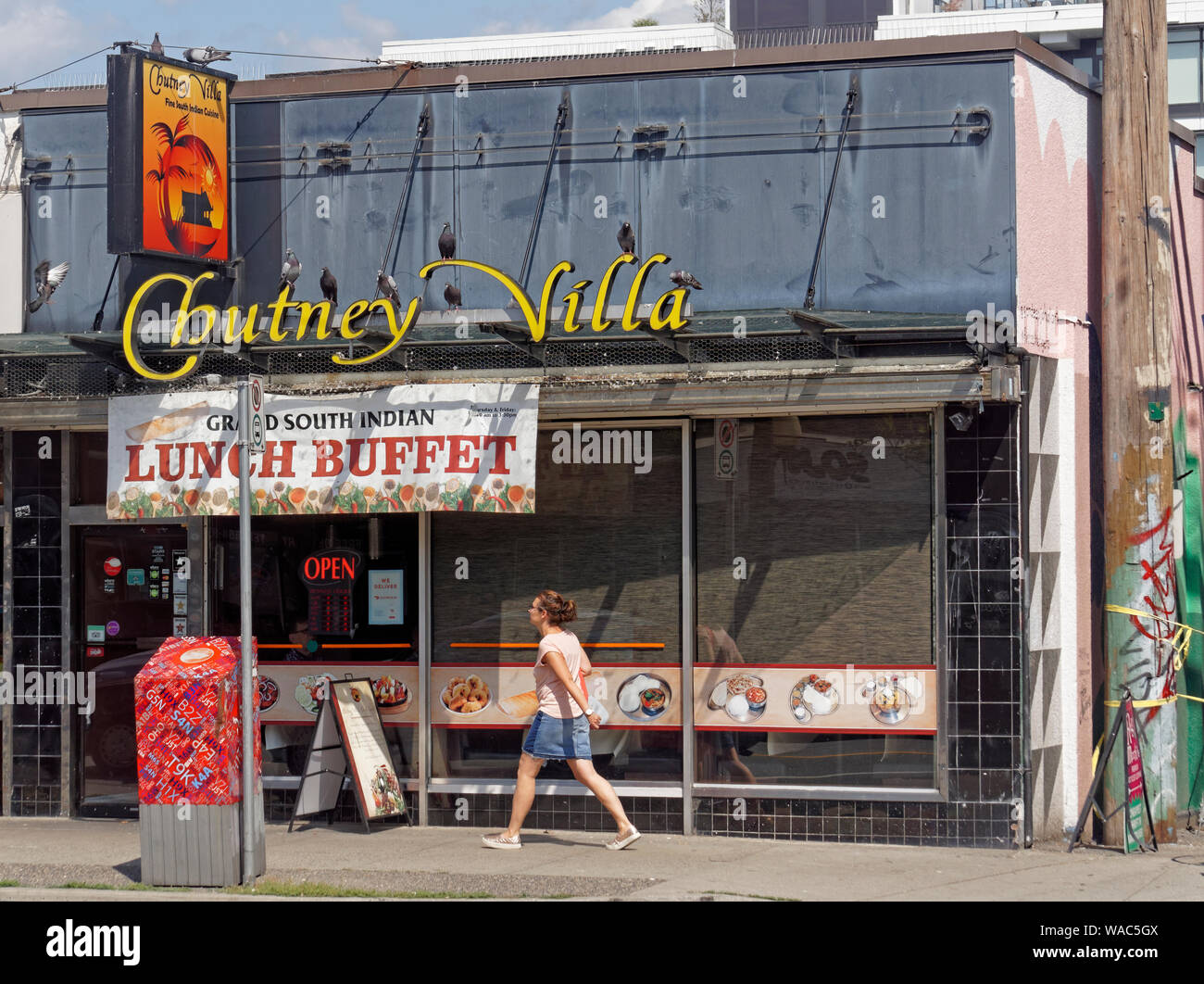 Donna oltrepassando il Chutney Villa Sud ristorante indiano sulla east Broadway Street in Mount Pleasant, Vancouver, BC, Canada Foto Stock