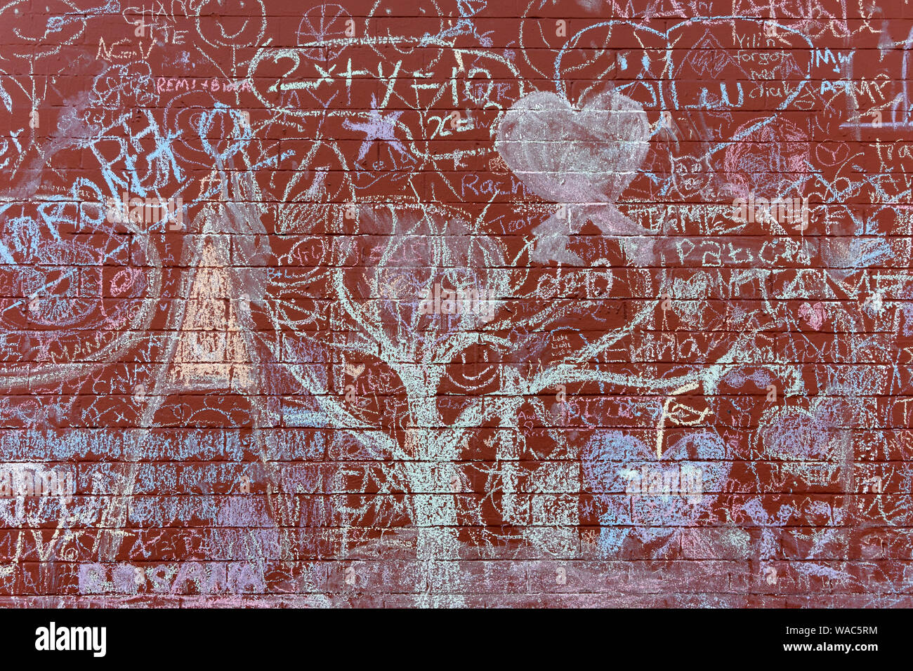 Rosso mattone muro di un edificio coperto di gesso colorati graffiti nel distretto di Mount Pleasant di Vancouver, BC, Canada Foto Stock