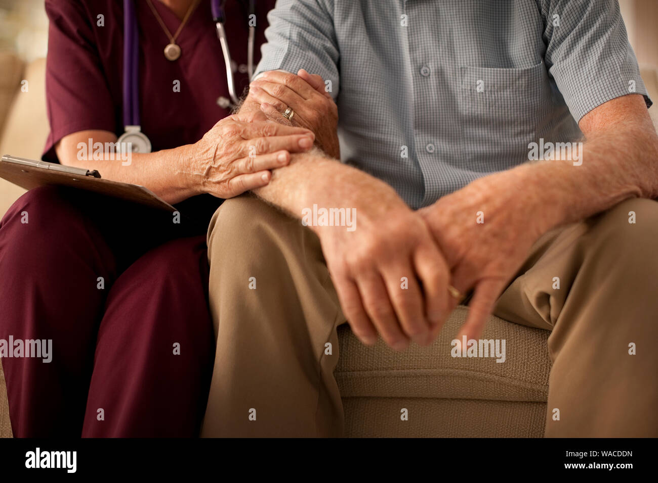 Senior uomo seduto con un infermiere. Foto Stock