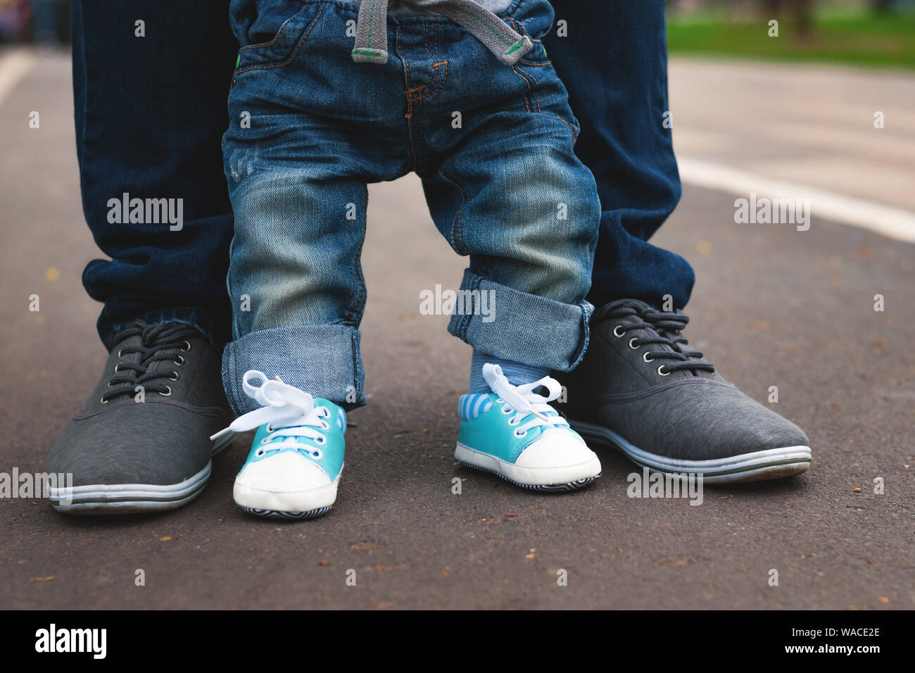 Piedi anno vecchio ragazzo e padre sulla pista di asfalto. Papà insegna al  bambino a camminare. Jeans e scarpe da ginnastica. Il congedo di paternità  Foto stock - Alamy