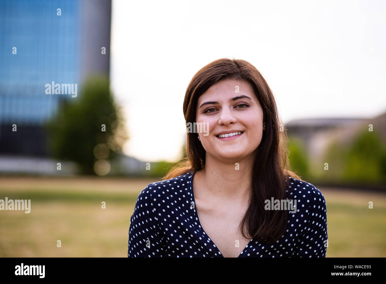 Ritratto di sorridente giovane donna che guarda la fotocamera all'aperto Foto Stock