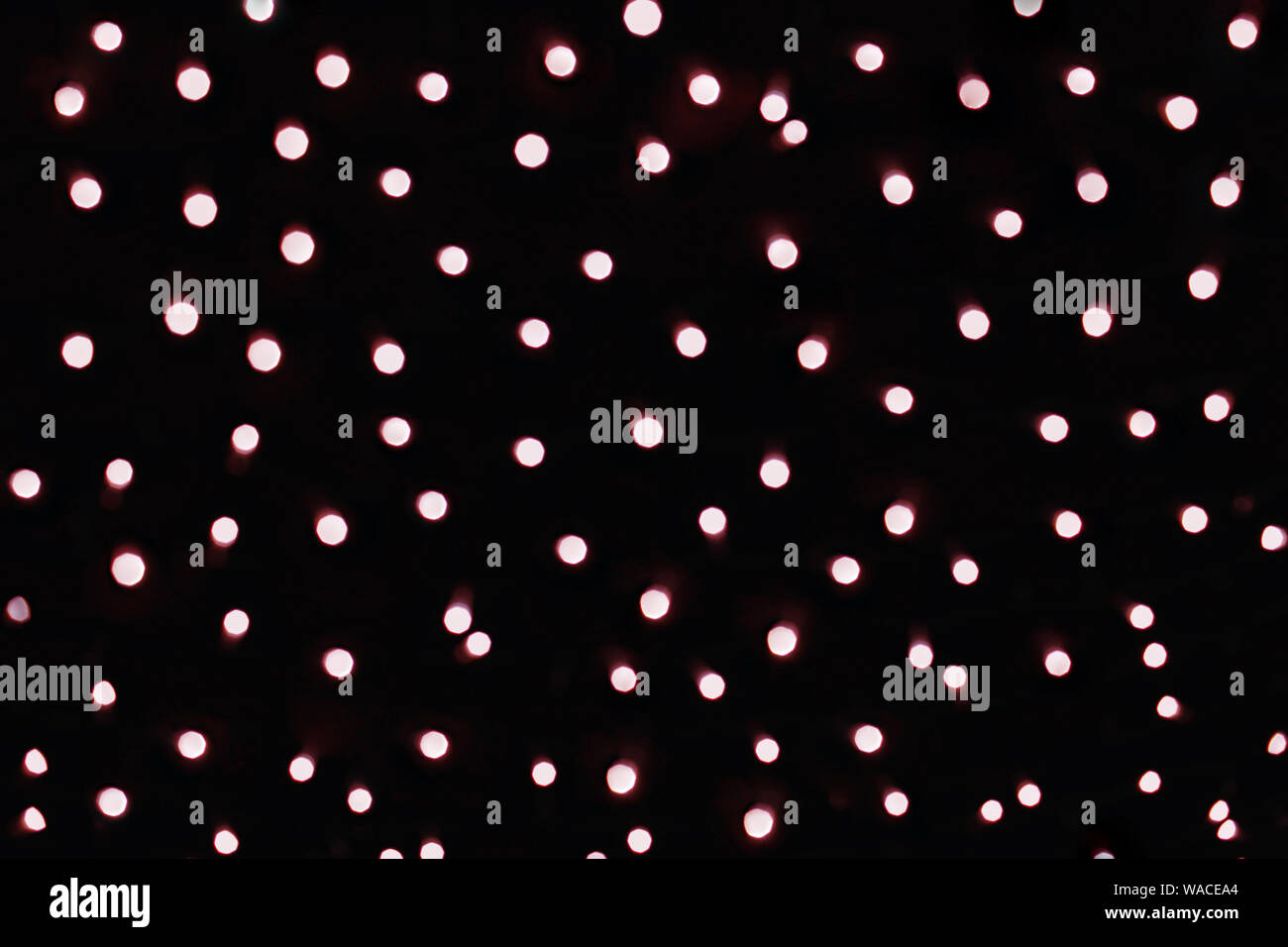 Luci d'oro con la tinta rossa sfocato bokeh, sfondo scuro con molti cerchi lampeggianti. Foto Stock