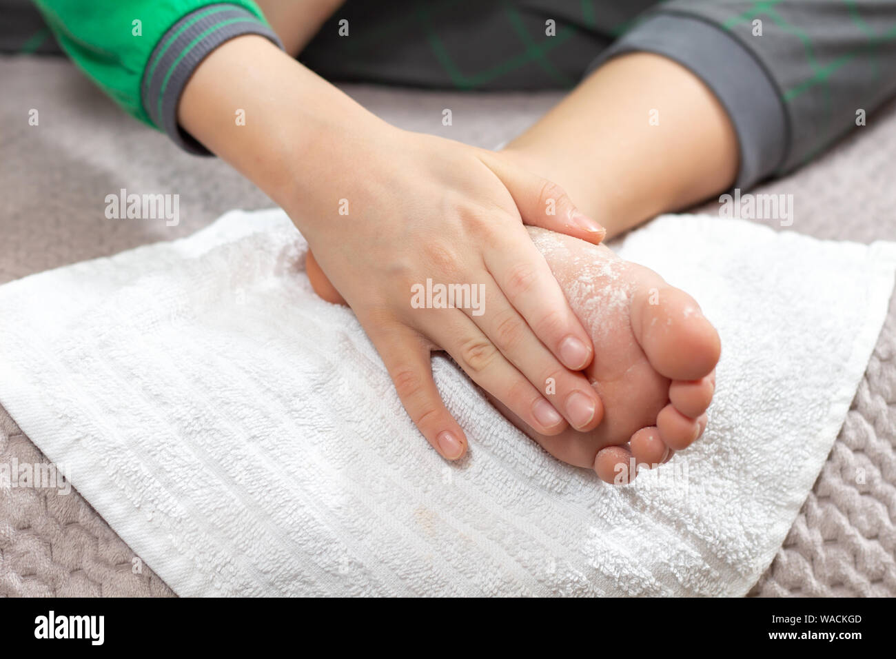 Il bambino sfrega contro la polvere bianca in piedi. La pelle del piede igiene. Foto Stock