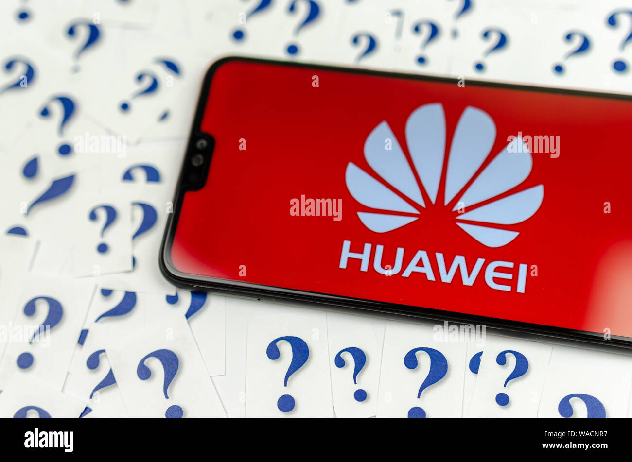 HUAWEI logo sul HUAWEI smartphone e un sacco di carta punti interrogativi intorno a. La fotografia concettuale circa il futuro della tech gigante negli Stati Uniti. Foto Stock