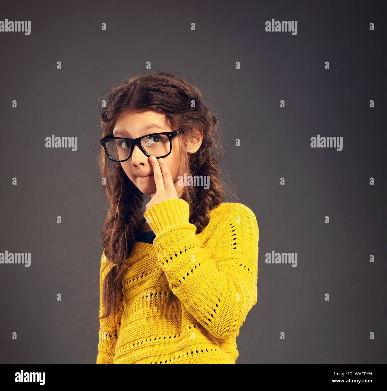 Pensando smorfie schoolgirl in occhiali cercando su grigio di sfondo per studio in abbigliamento moda. Si torna a scuola. Il concetto di istruzione. Closeu Foto Stock