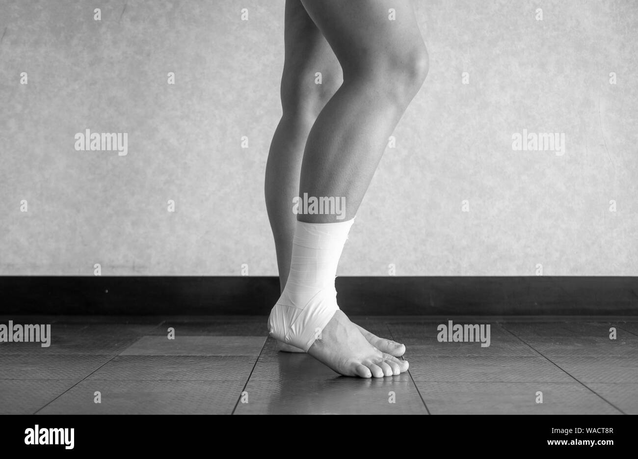 Versione in bianco e nero di atleta con una caviglia slogata che lottano per sopportare il peso Foto Stock