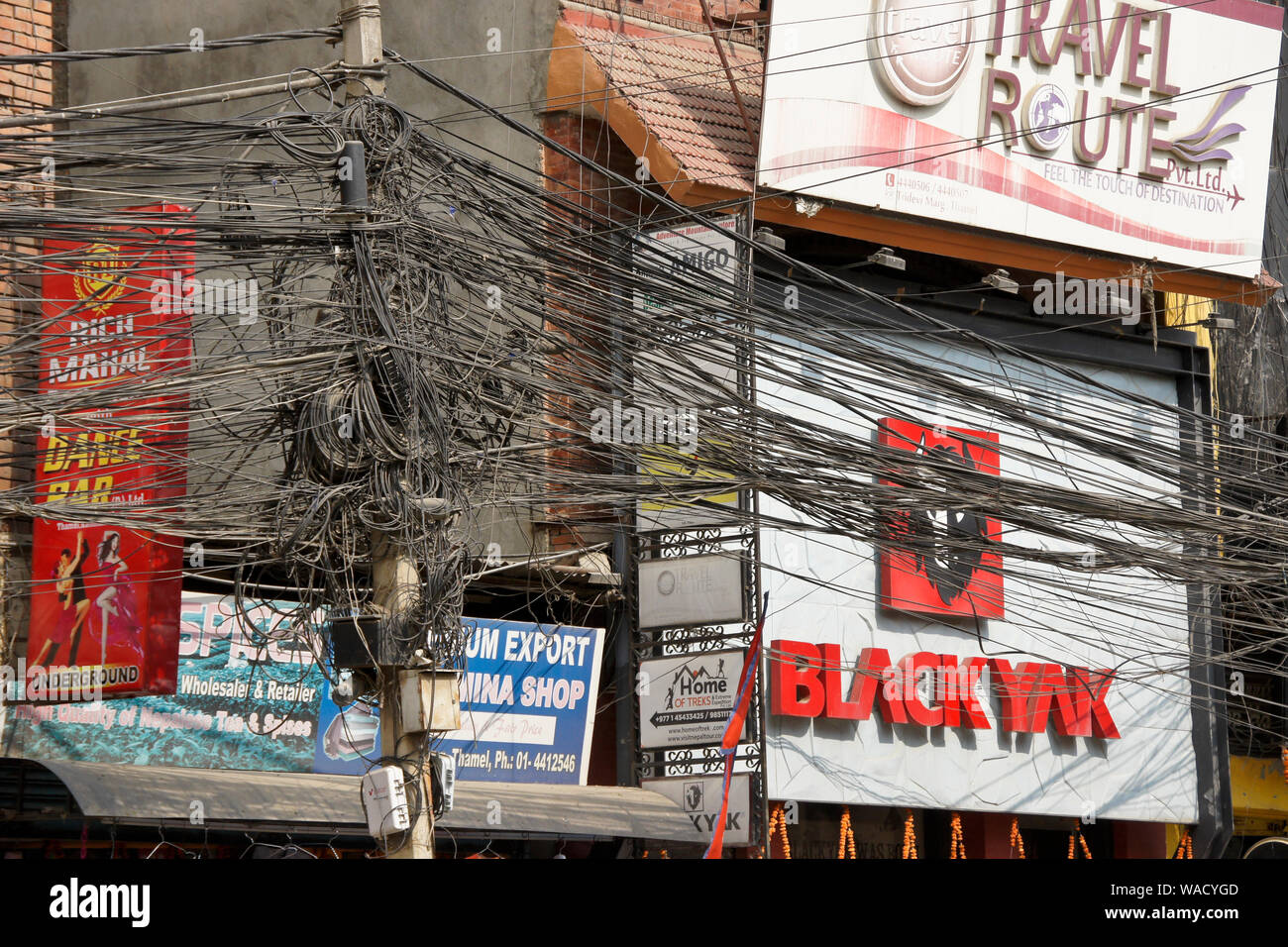 Un groviglio di fili elettrici tra segni nel quartiere degli affari di Thamel, Kathmandu, Nepal Foto Stock