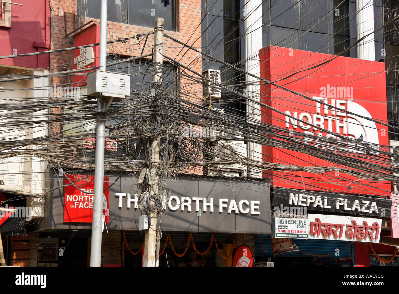 Un groviglio di fili elettrici tra segni nel quartiere degli affari di Thamel, Kathmandu, Nepal Foto Stock