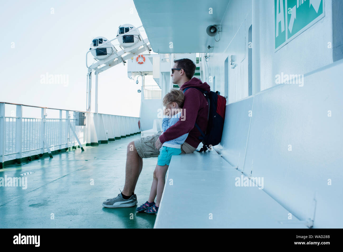 Padre abbracciando la figlia sul ponte di una nave traghetto in mare Foto Stock